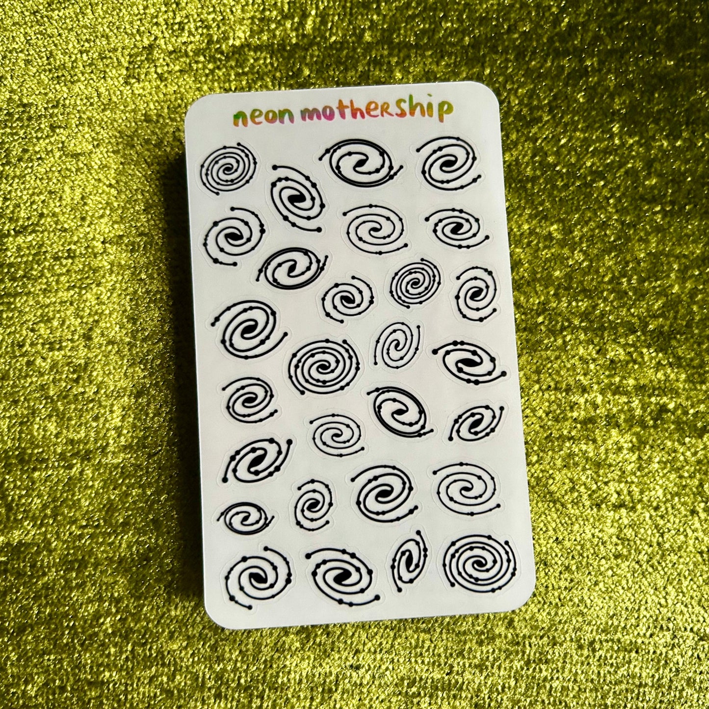 sticker sheet with black spiral patterns on a green textured background