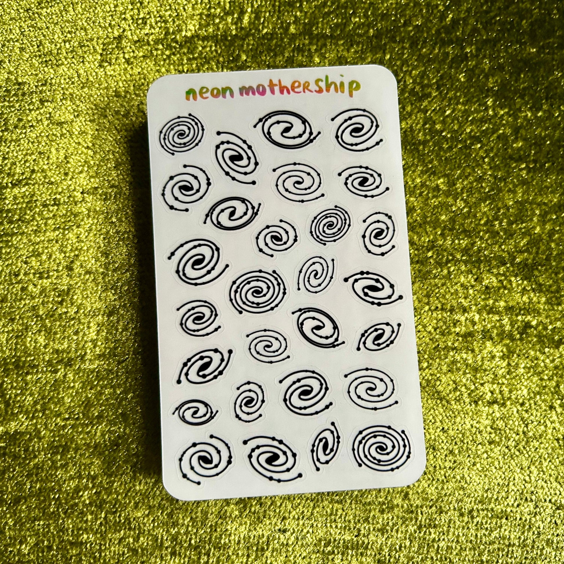 sticker sheet with black spiral patterns on a green textured background