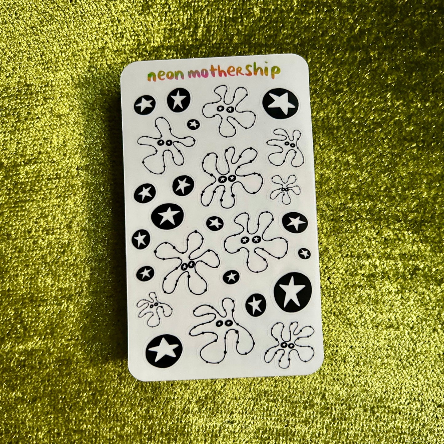 Sheet of black and white flower and star stickers on a green textured background