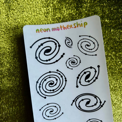 Sheet of black spiral designs on a white card with 'neon mothership' branding against a green textured background.