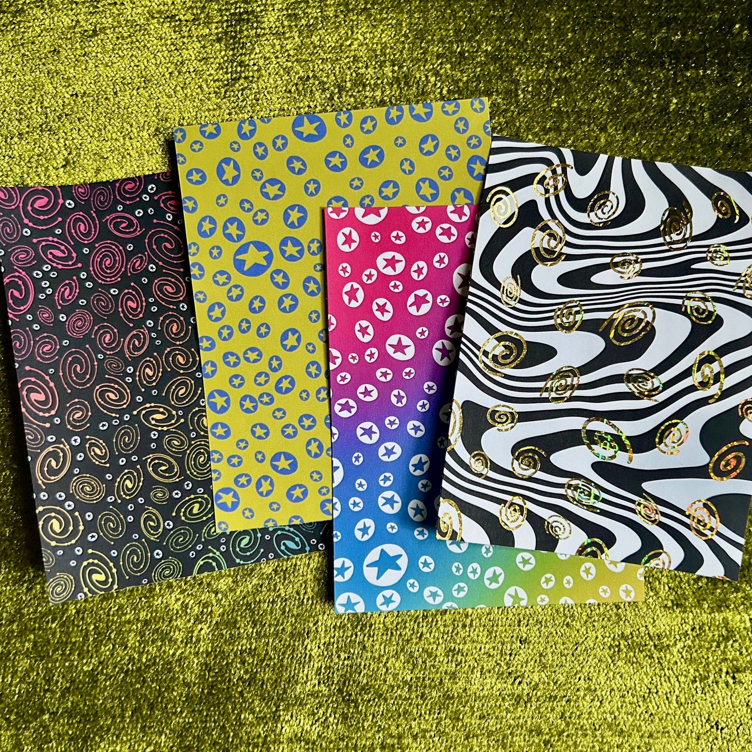 Four patterned sticker sheets on a textured green surface