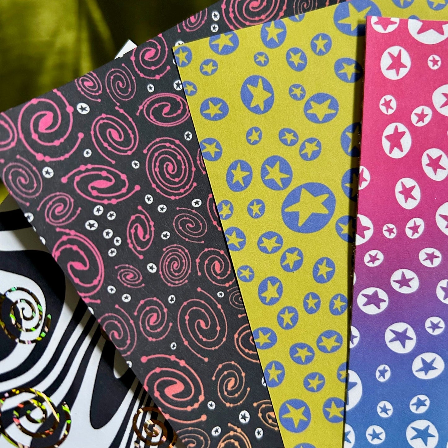 Colorful patterned paper sheets with various designs on a green background