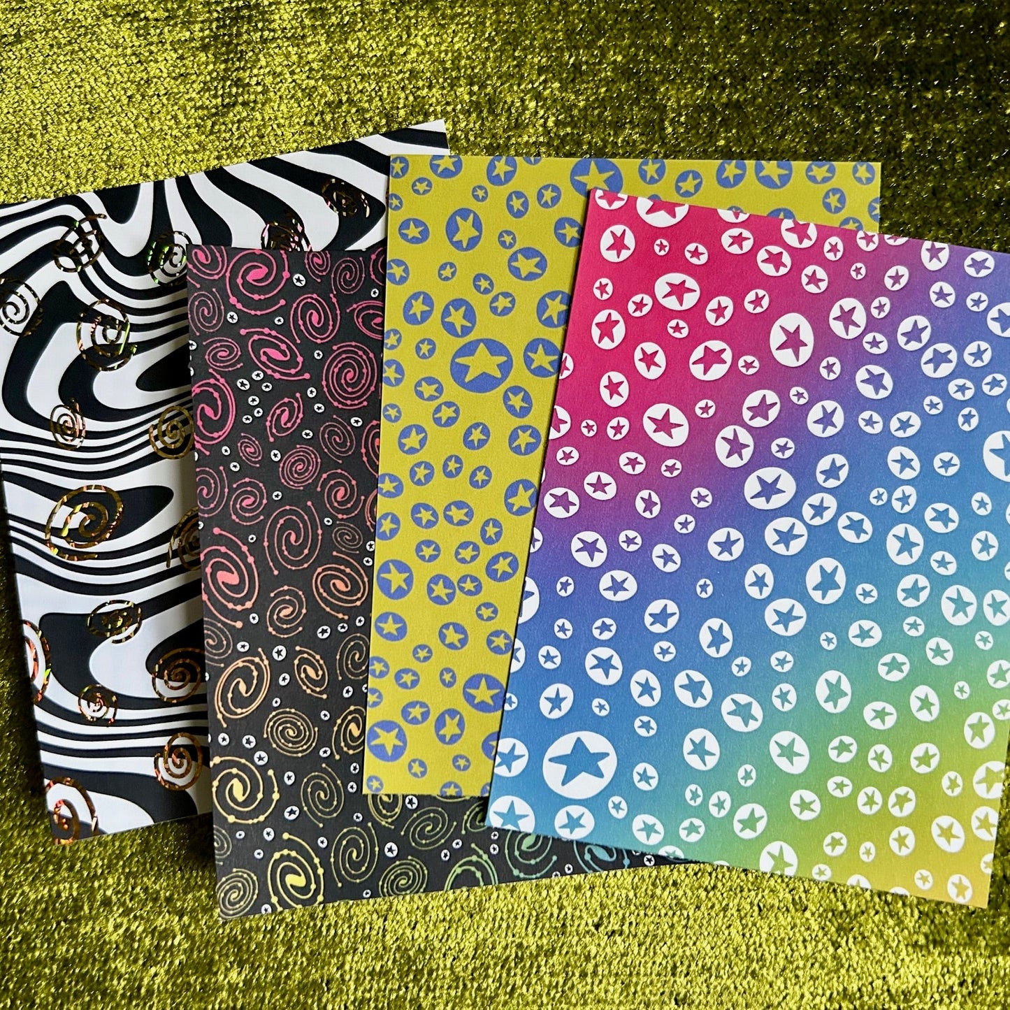 Four patterned sticker sheets on a textured green surface