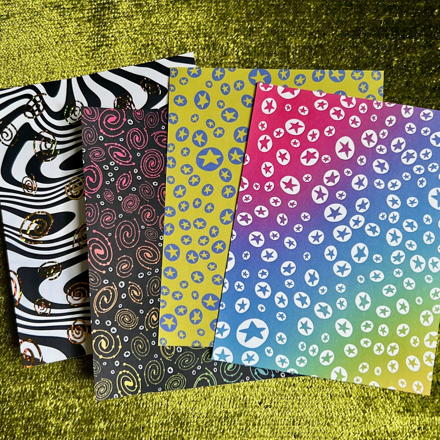 Four patterned sticker sheets on a textured green surface