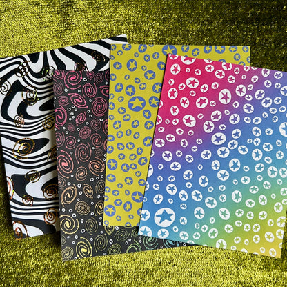 Four patterned sticker sheets on a textured green surface