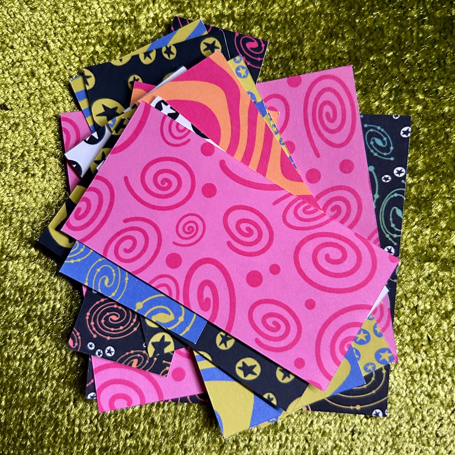 Colorful patterned sticker scraps on a green textured surface