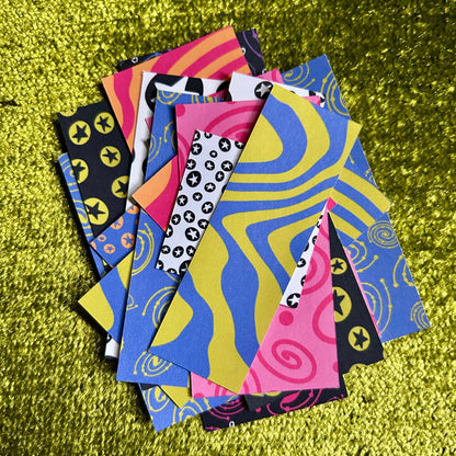 Colorful patterned sticker scraps on a green textured surface