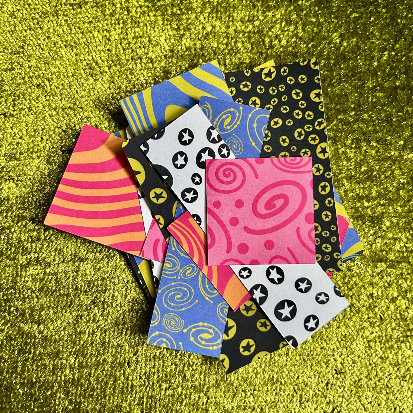 Colorful patterned sticker sheets on a green textured surface