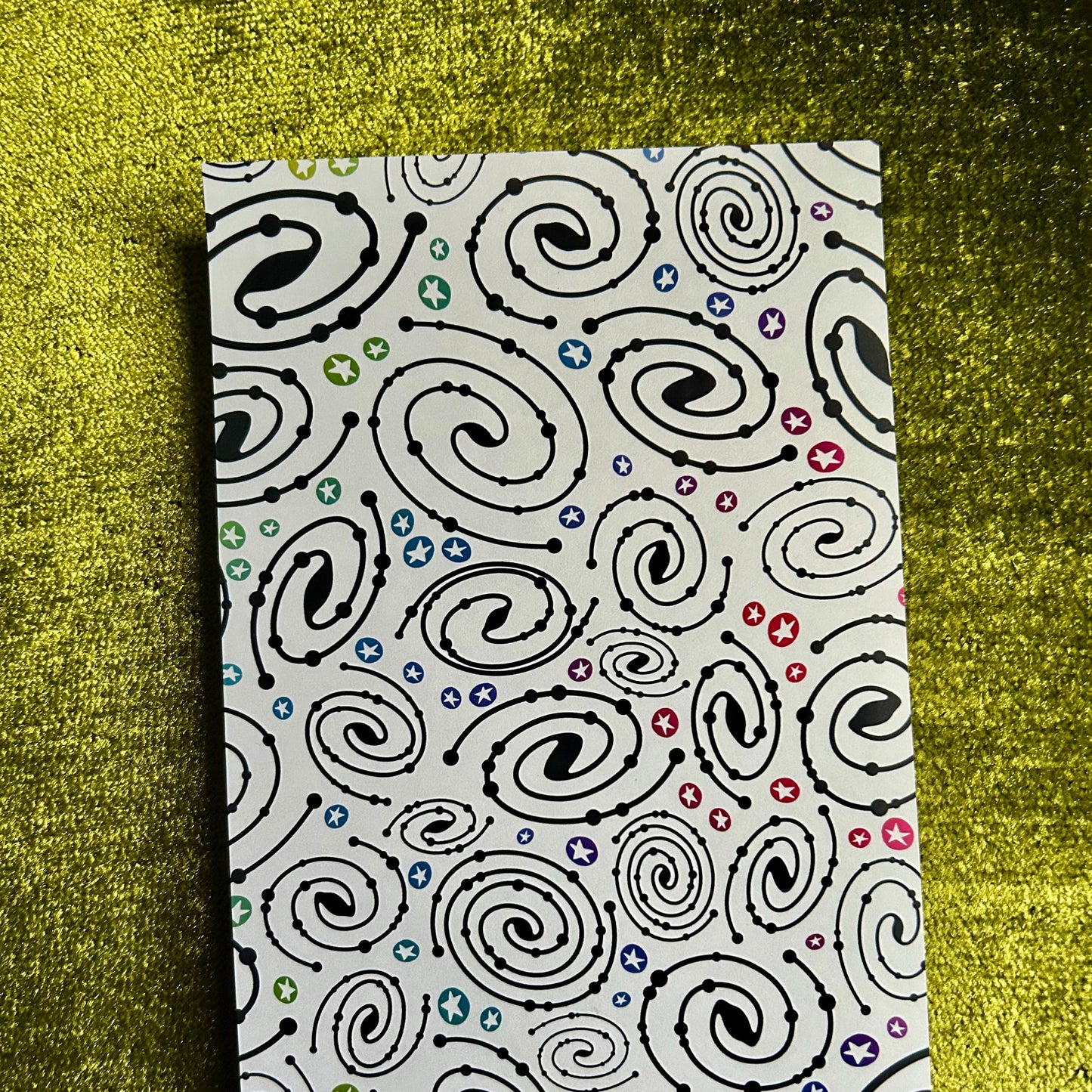 sticker paper with a black spiral pattern on a green textured surface