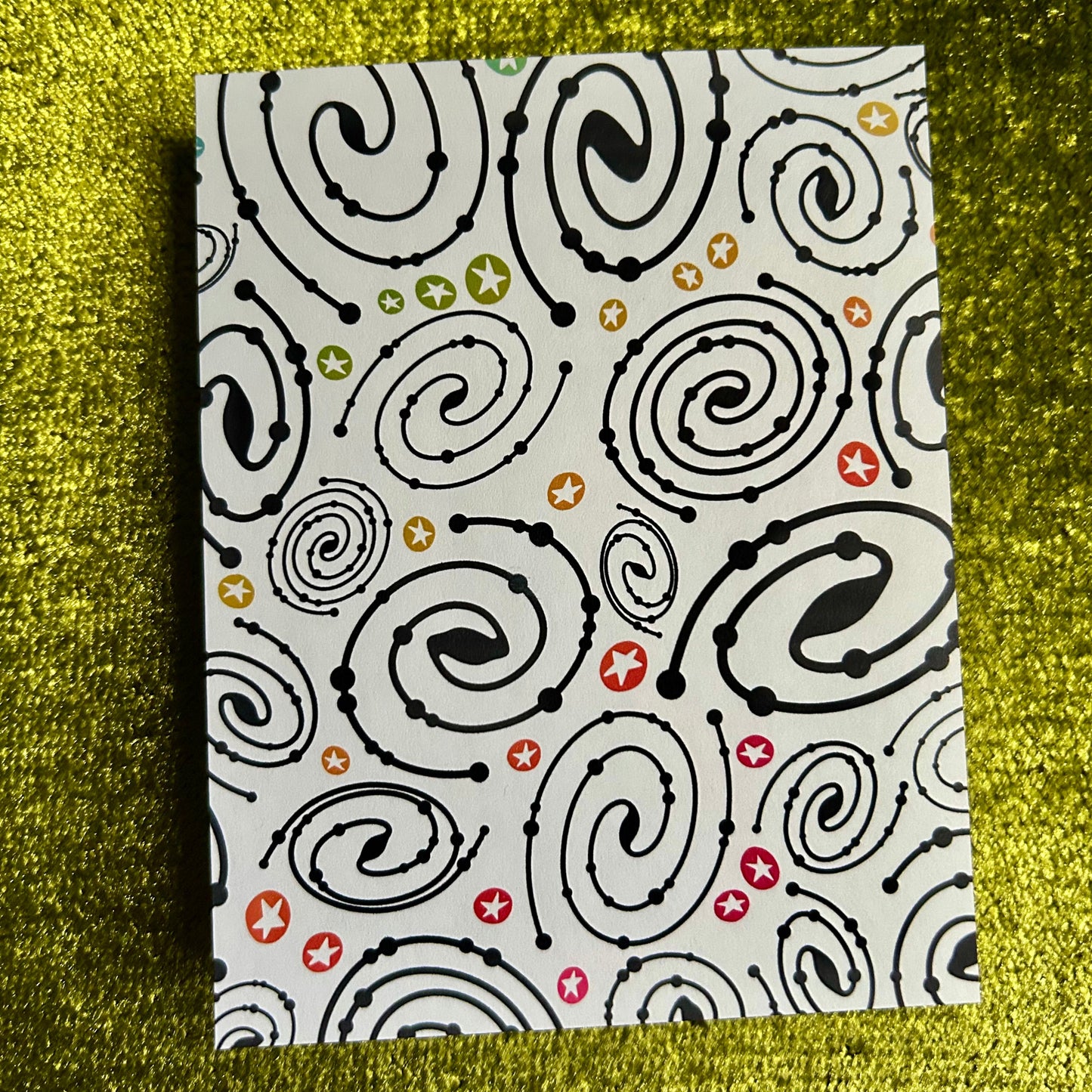sticker paper with black spiral pattern on a textured green surface