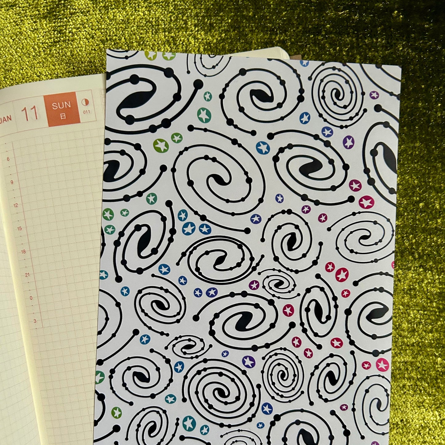 Notebook with a black spiral pattern on a green textured surface