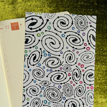 Notebook with a black spiral pattern on a green textured surface