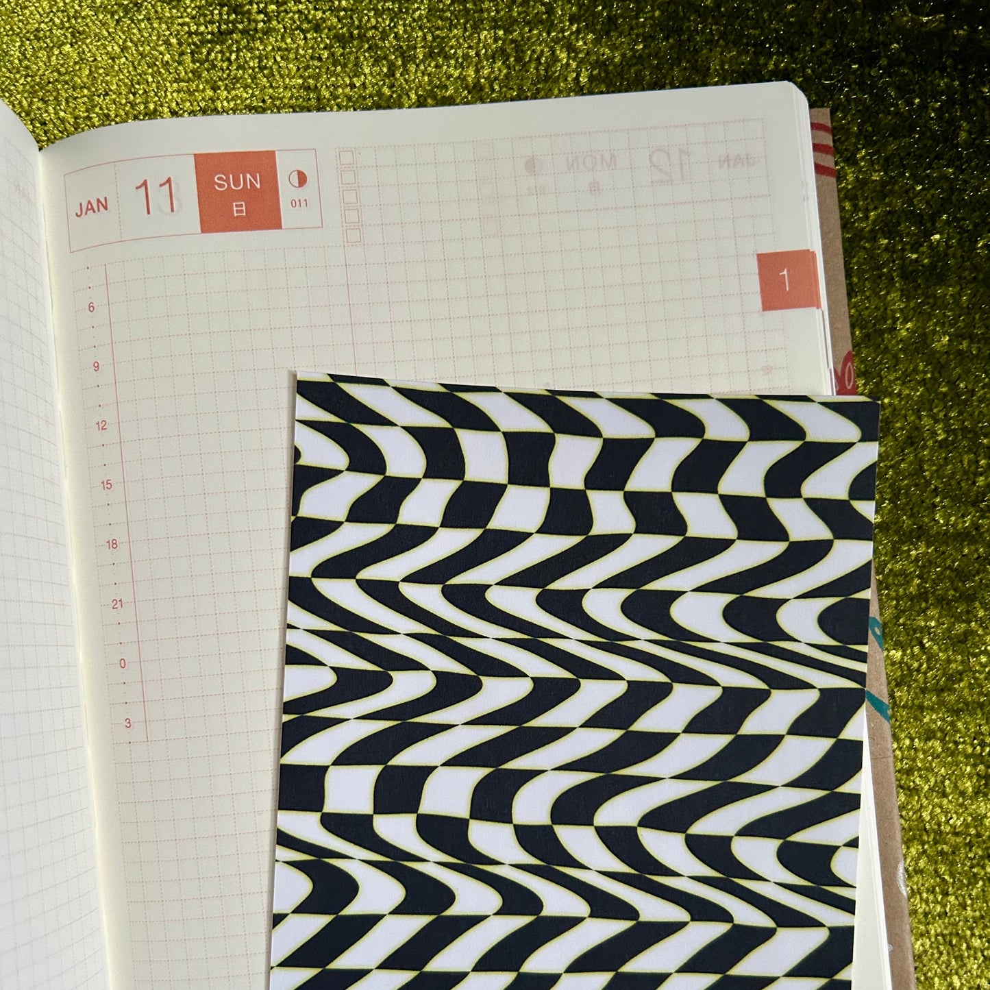sticker sheet with a black and white patterned cover on a green textured surface