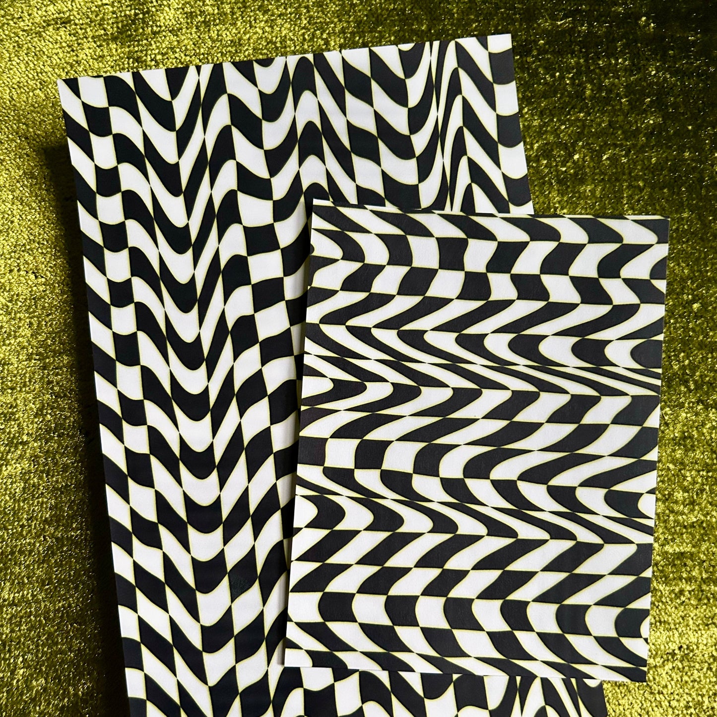 Two black and white sticker sheets on a textured green surface