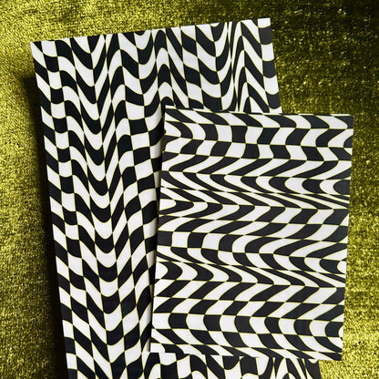 Two black and white sticker sheets on a textured green surface