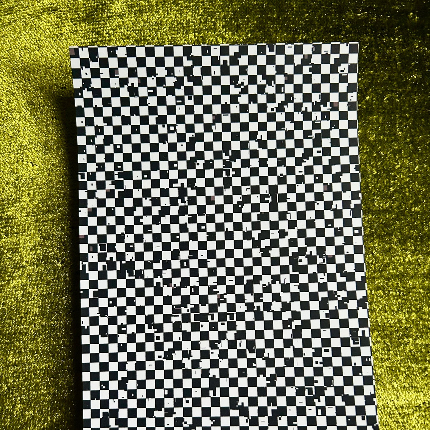 Checkered sticker paper on a textured green surface