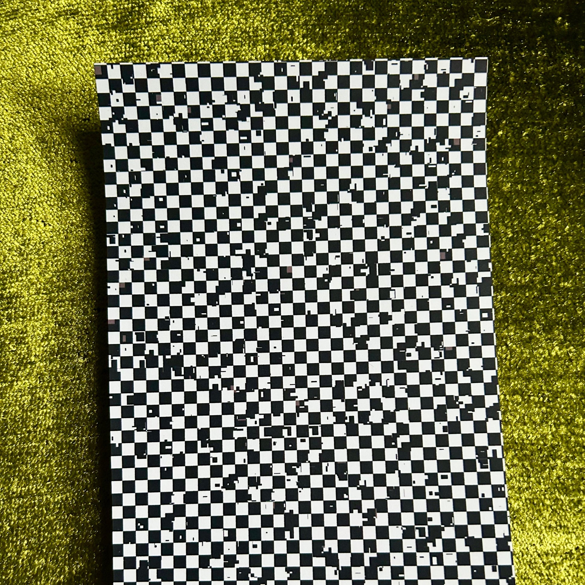 Checkered sticker paper on a textured green surface