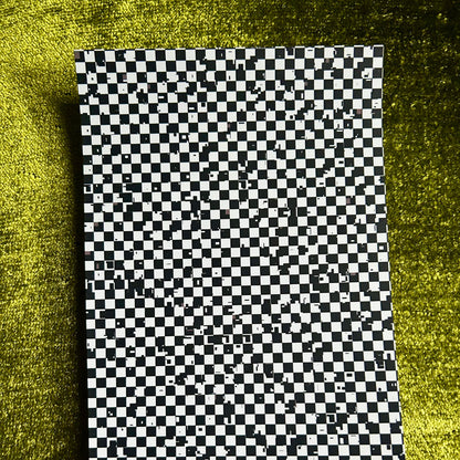 Checkered sticker paper on a textured green surface