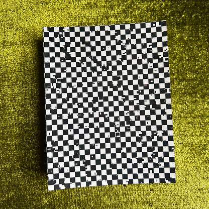 Checkered black and white paper on a green textured surface