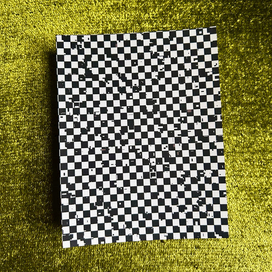 Checkered black and white paper on a green textured surface