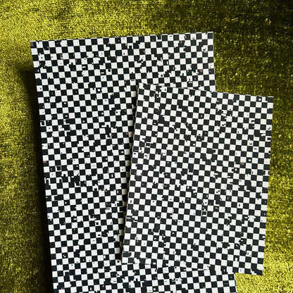 Two checkered paper sheets on a textured green surface