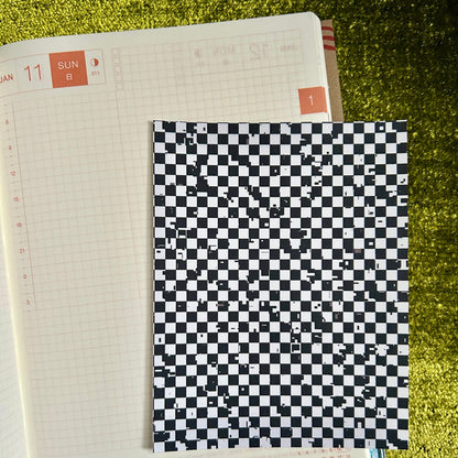 Checkered sticker sheet on an open notebook with a green textured background