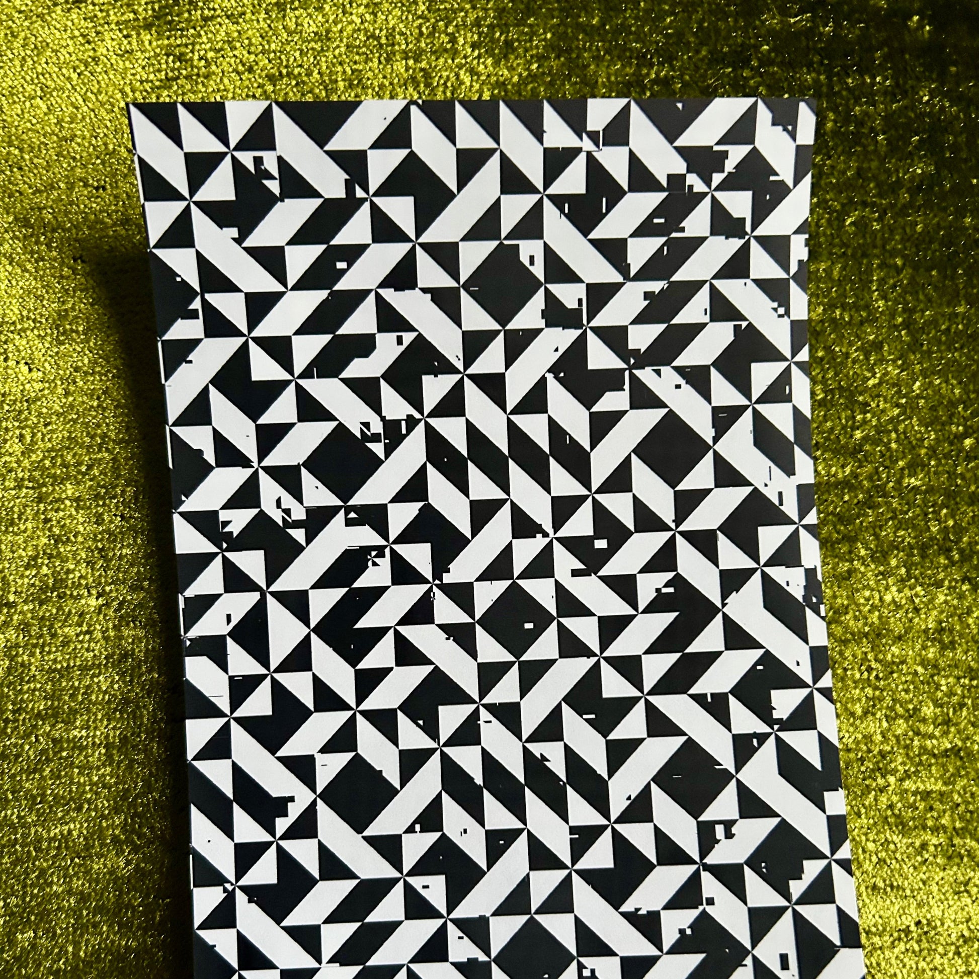 Black and white geometric patterned notebook on a green textured surface
