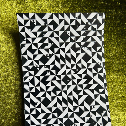 Black and white geometric patterned notebook on a green textured surface
