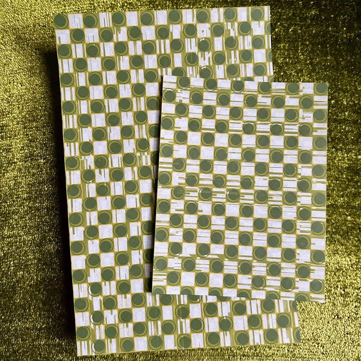 Two green and white patterned sticker sheets on a textured green surface