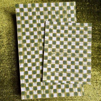 Two green and white patterned sticker sheets on a textured green surface