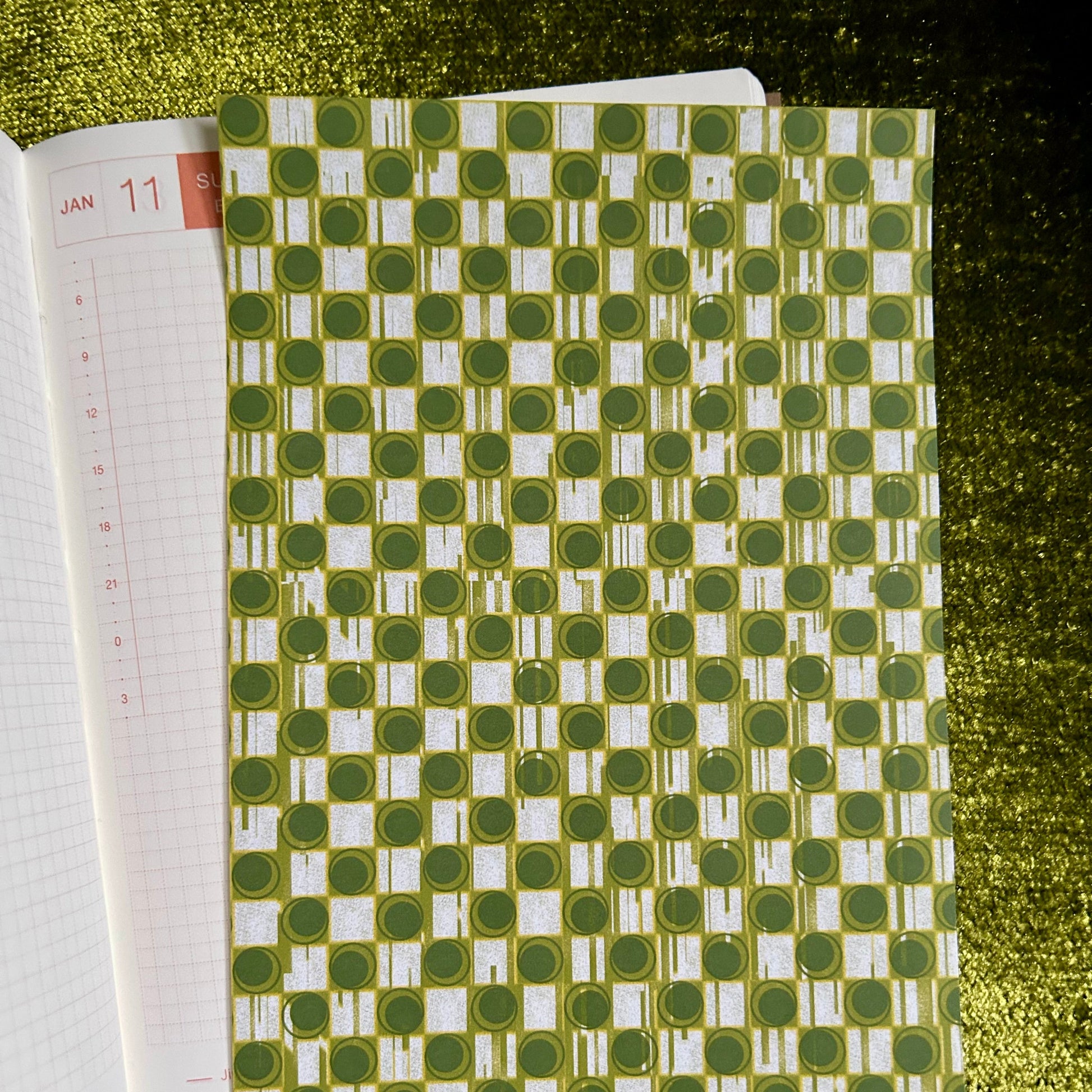 Green and white patterned sticker sheet on a textured green surface