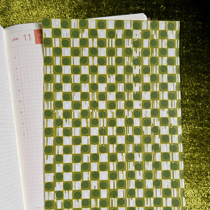 Green and white patterned sticker sheet on a textured green surface