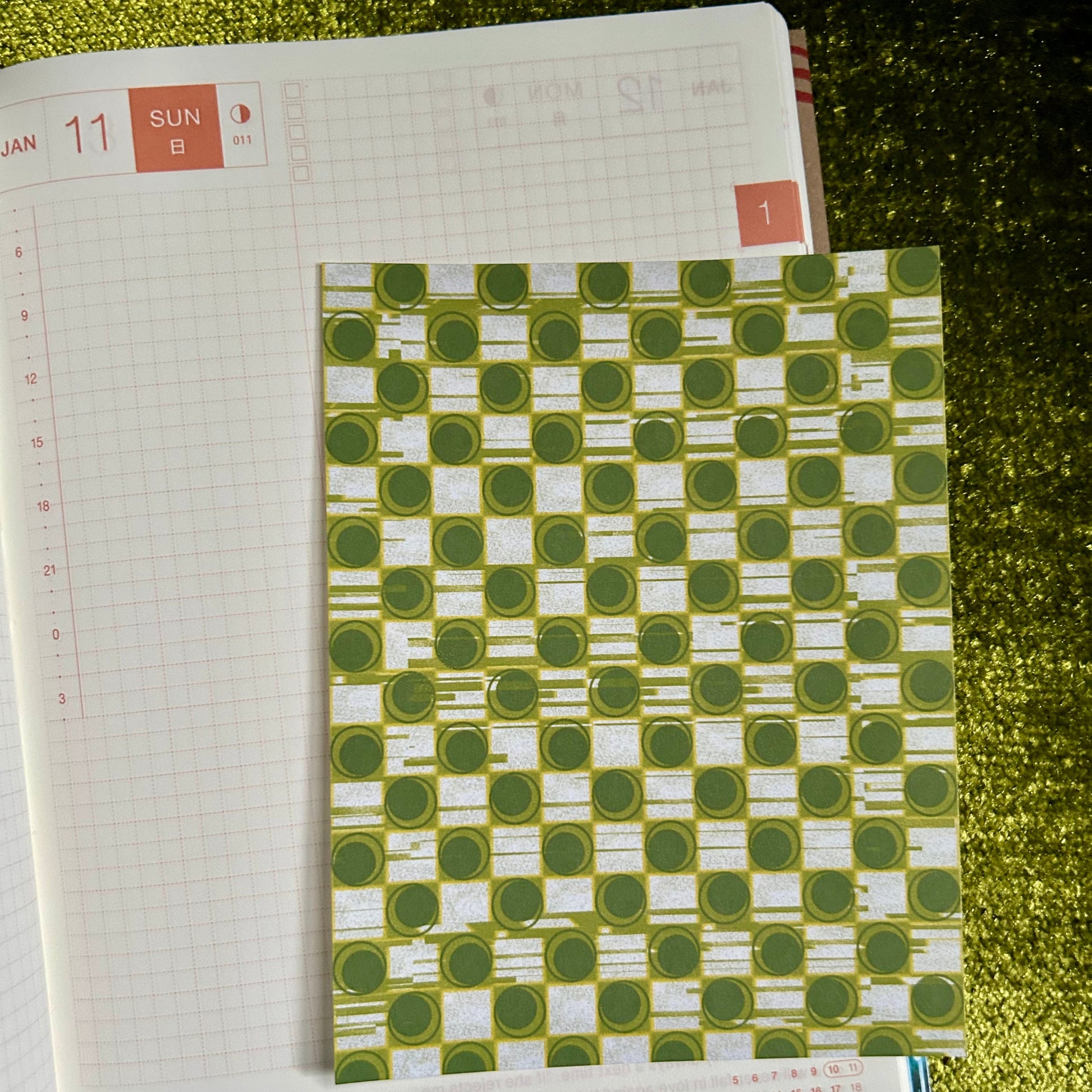 sticker sheet with a green and white patterned cover on a textured surface