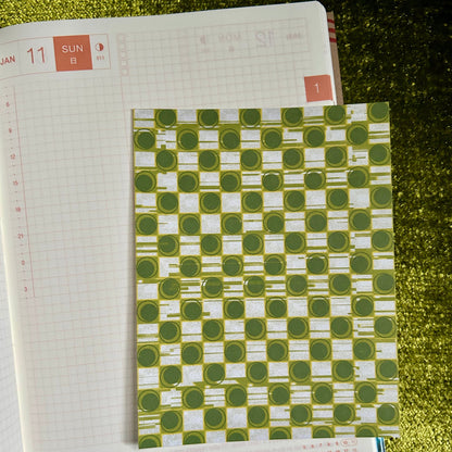 sticker sheet with a green and white patterned cover on a textured surface