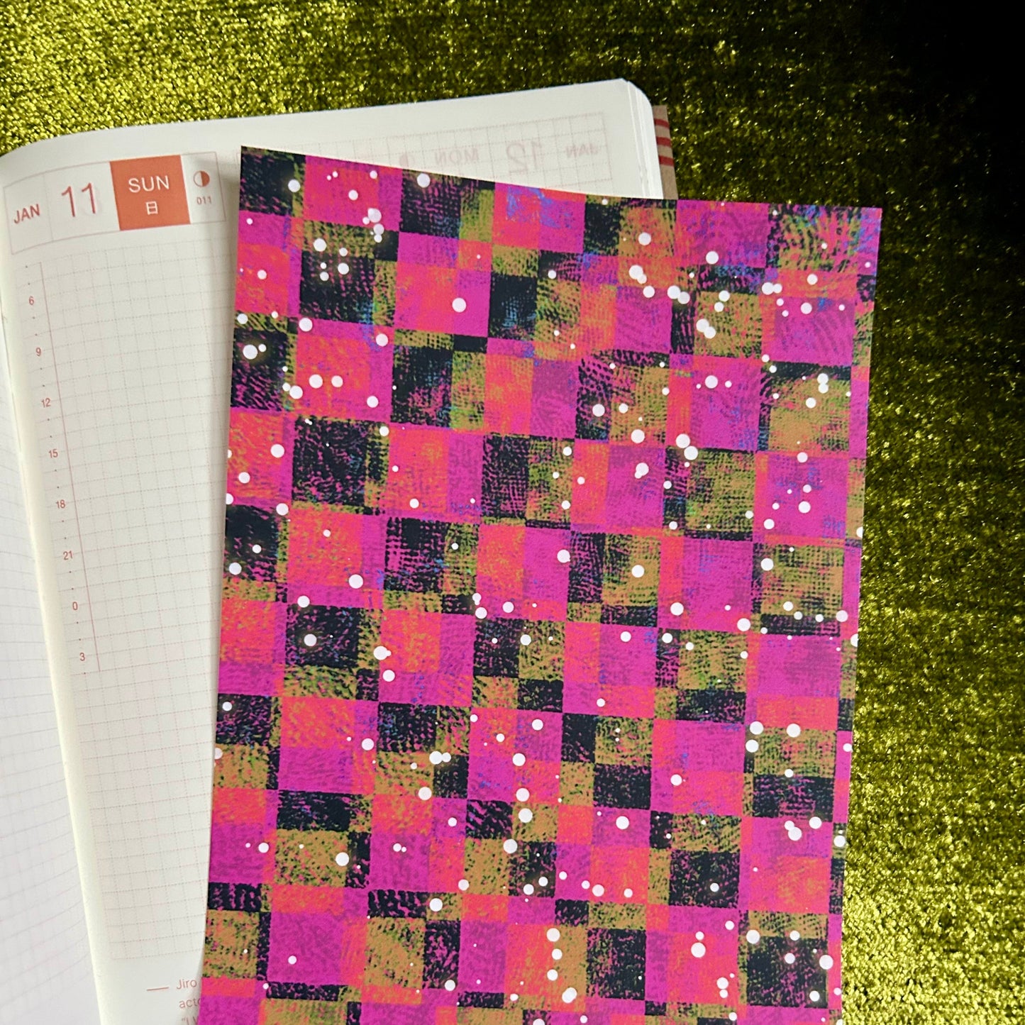 sticker paper with a colorful checkered cover on a green textured surface