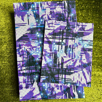 Pair of purple and black patterned sticker sheets on a green glittery background
