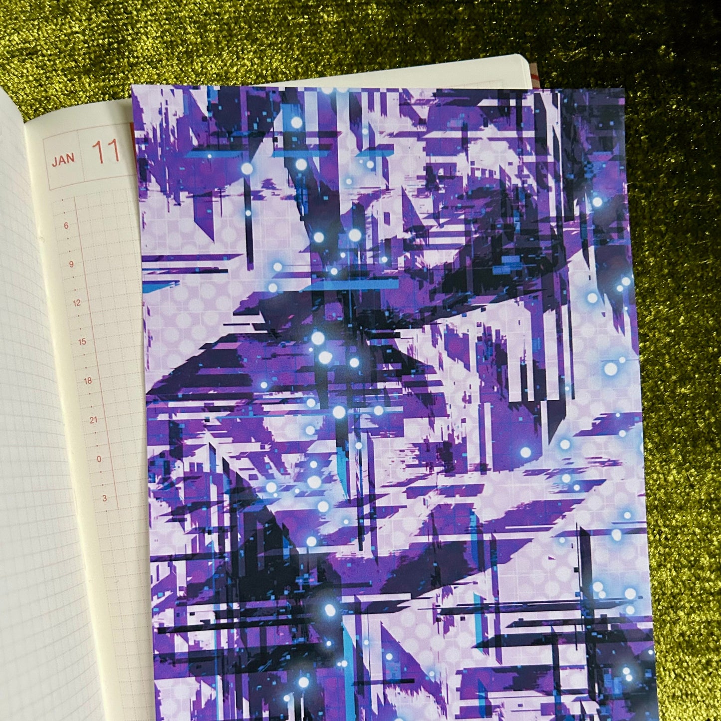 Notebook with a purple abstract pattern on a green textured surface