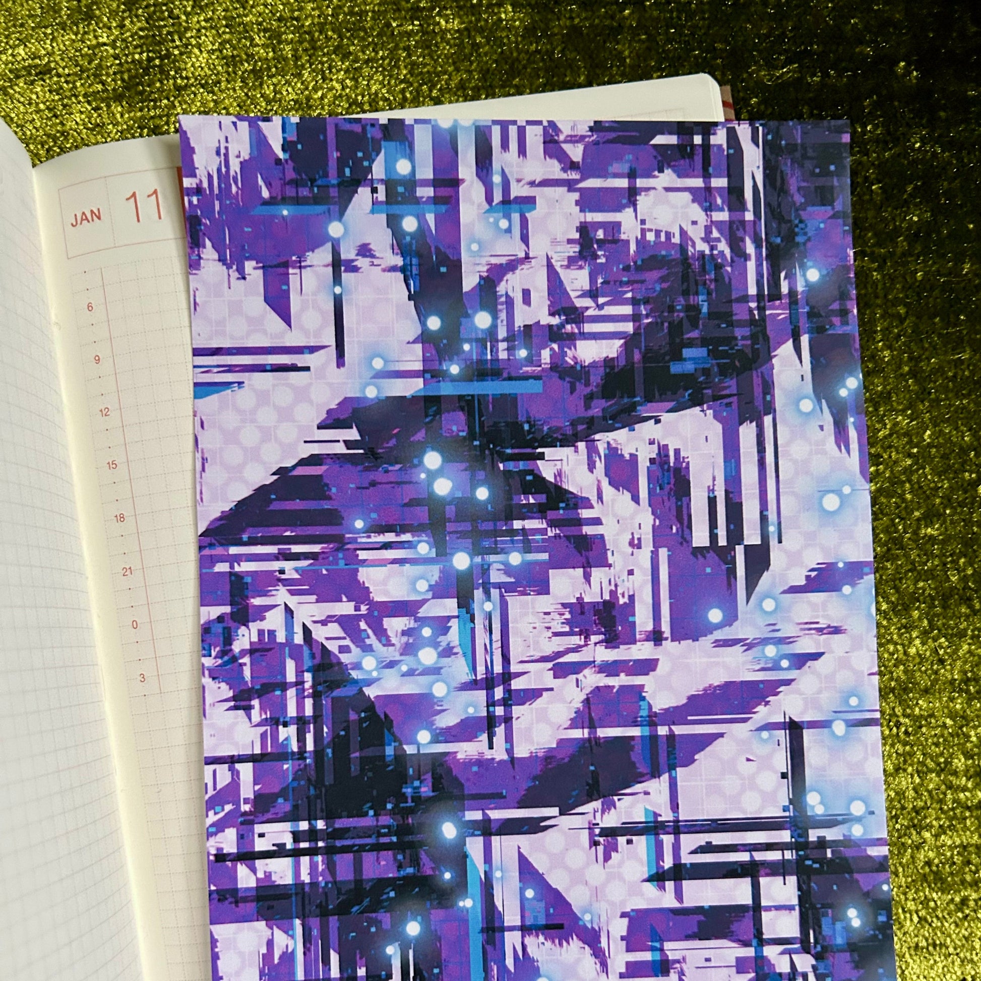 Notebook with a purple abstract pattern on a green textured surface