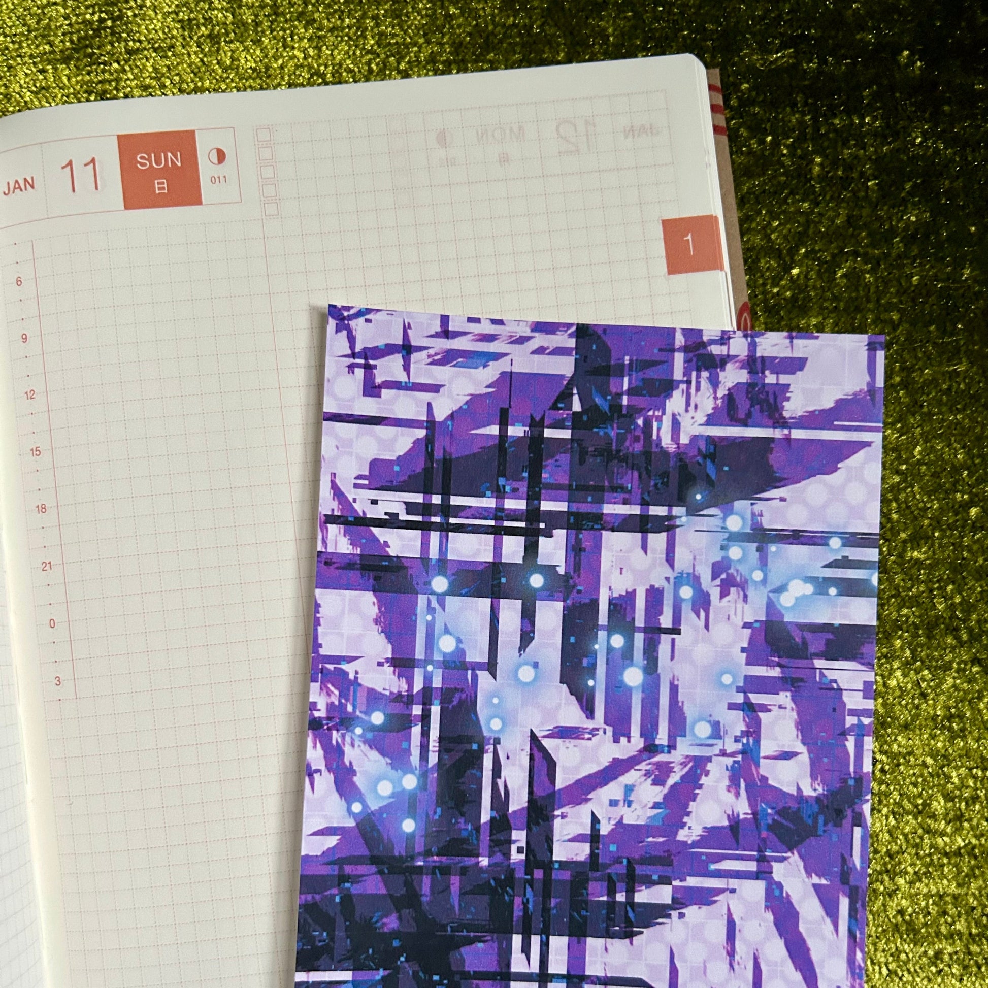 Notebook with a purple abstract design on a green textured surface