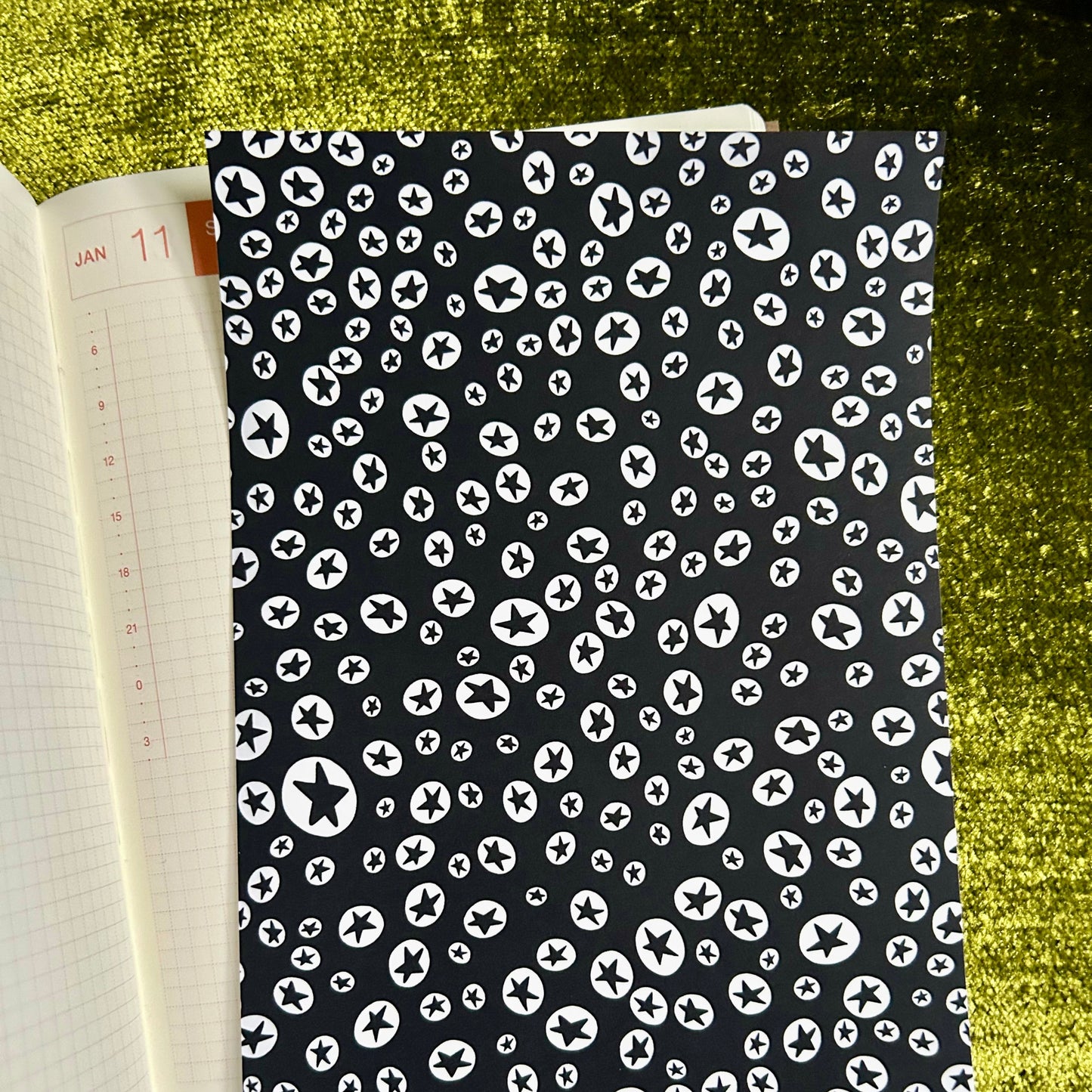 sticker sheet with black cover featuring white pattern on a green textured surface