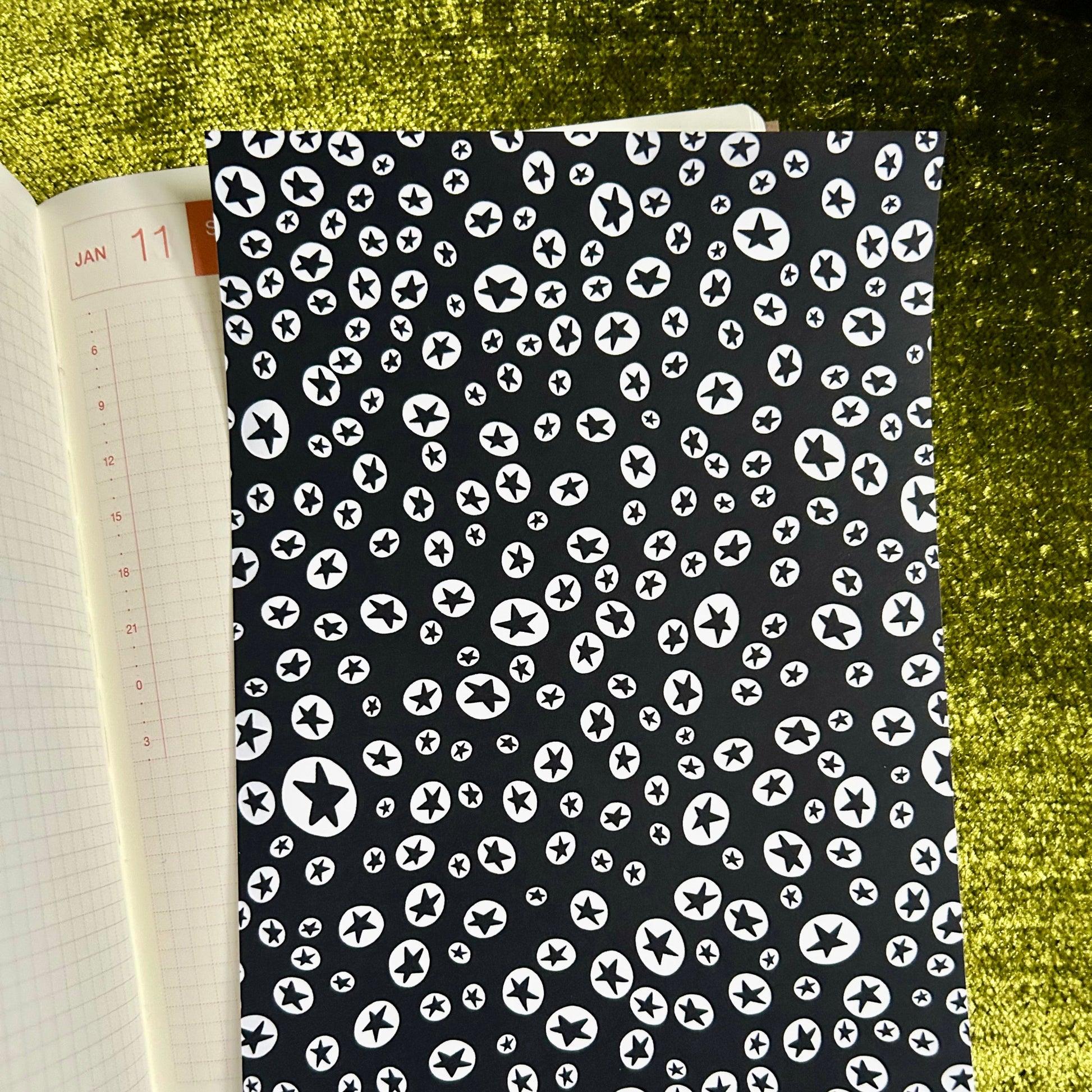 sticker sheet with black cover featuring white pattern on a green textured surface