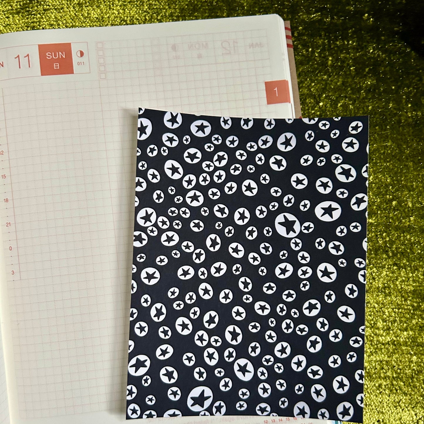 Patterned notebook cover with star design on a green textured surface