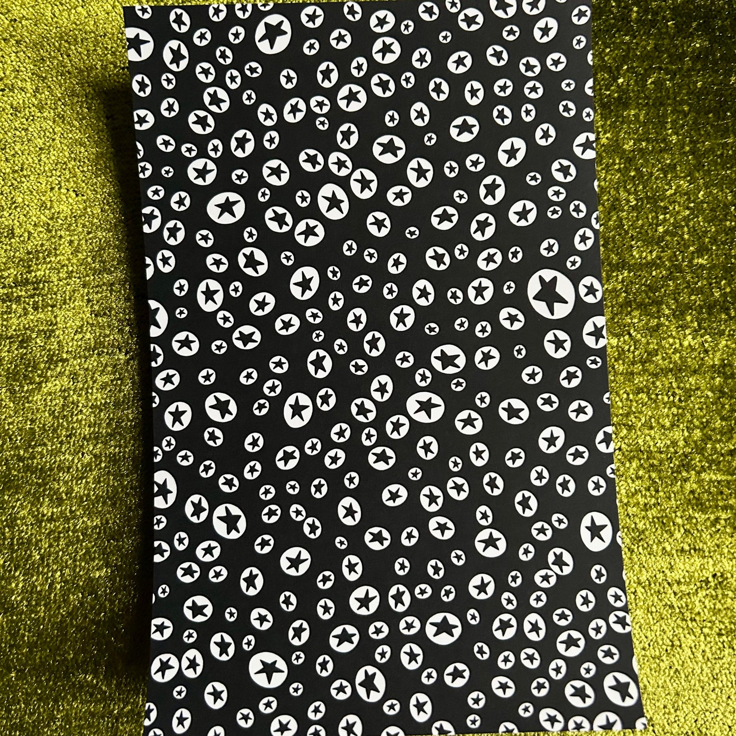 Black sticker sheet with white pattern on a green textured background