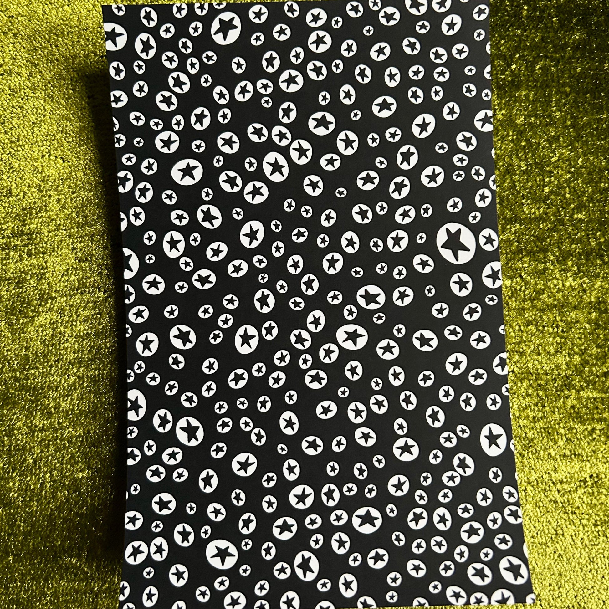Black sticker sheet with white pattern on a green textured background