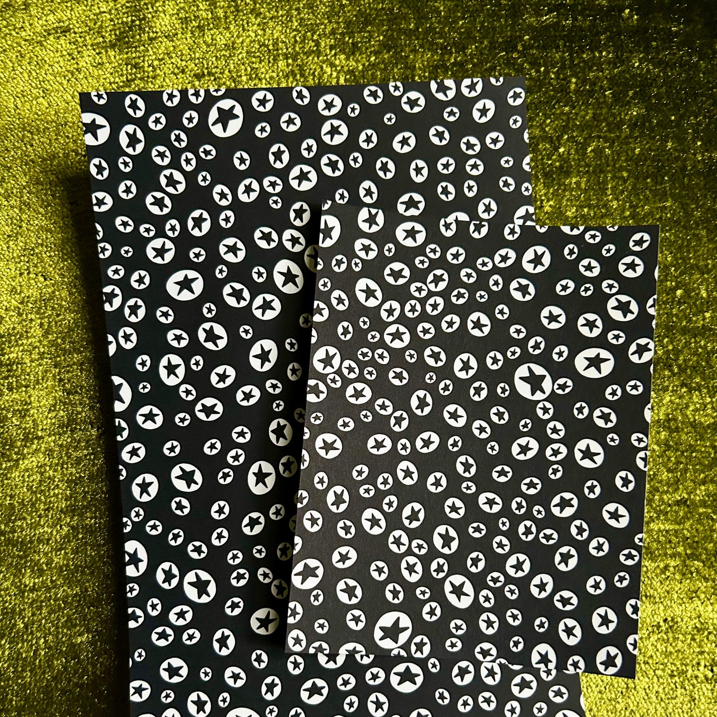 Two sticker sheets with white pattern on a textured green background