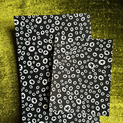 Two sticker sheets with white pattern on a textured green background