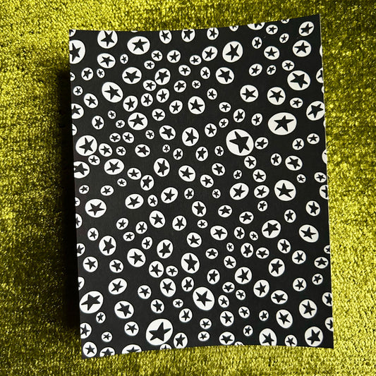 Black sticker sheet with white star pattern on a green textured background
