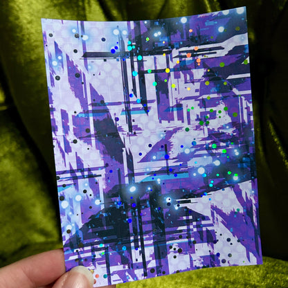 Hand holding a card with abstract purple design against a green fabric background