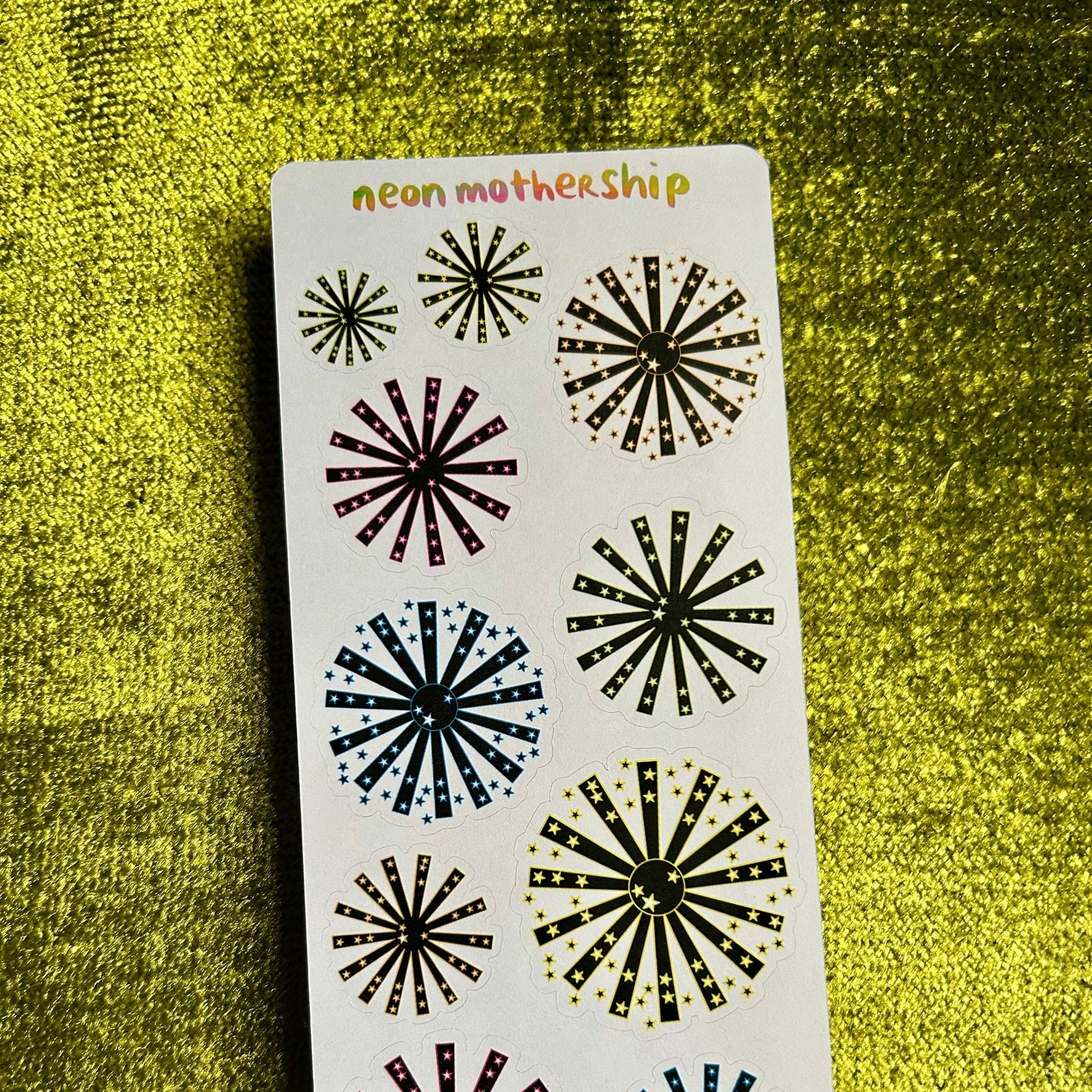 Sheet of decorative stickers with starburst designs on a green textured background
