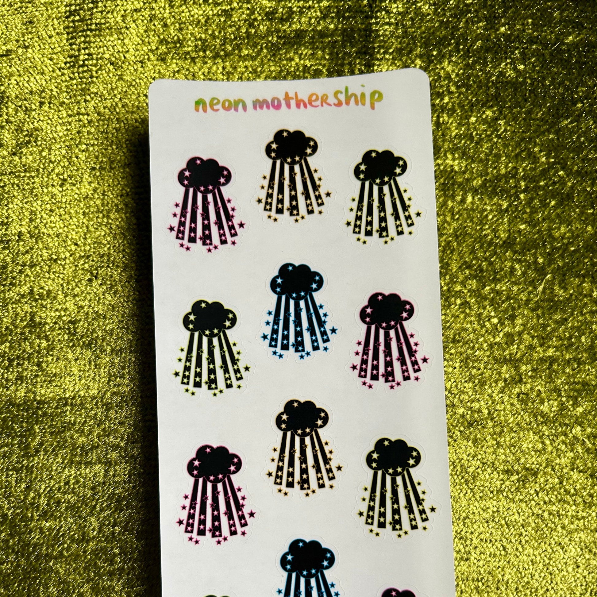 Sheet of cloud and raindrop stickers with 'neon mothership' branding on a textured green background.